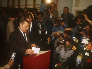 Lech Wałęsa wrzuca kartę do urny, otoczony przez dziennikarzy i fotoreporterów. To ważny moment dla III Rzeczypospolitej.