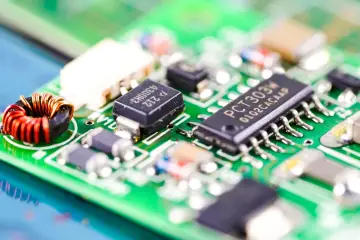 Zbliżenie na zieloną płytkę drukowaną z widocznym układem scalonym PCT303W, cewką i innymi komponentami elektronicznymi.
