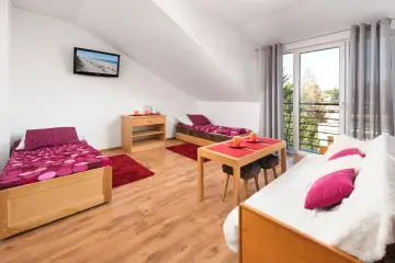 Pokój w domku wypoczynkowym Arka: dwa łóżka, stolik z krzesłami, TV i balkon.