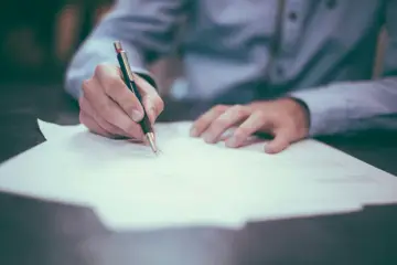 Dłoń pisze długopisem na papierze. Zastanawiasz się, co robic po prawie? To może być początek kariery.