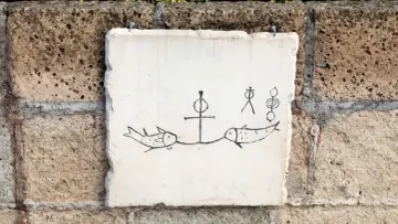 Kamienna tablica z rysunkami ryb i symboli, przypominająca inskrypcje z katakumb.