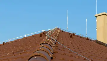 Nowy dach z brązowej dachówki, na którym zamontowano nowoczesną instalację odgromową, chroniącą przed burzami.