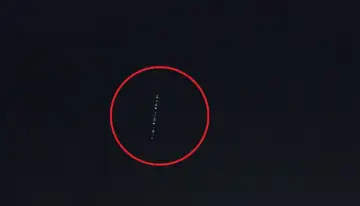 Linia jasnych punktów na ciemnym niebie, przypominająca pociąg satelitów Starlink.