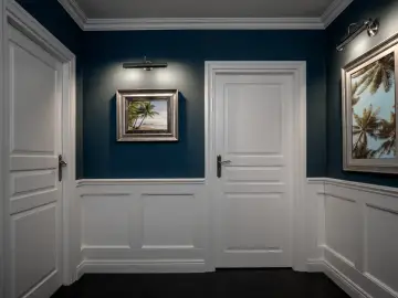 Elegancka boazeria angielska inspiracje: białe drzwi, ciemnoniebieskie ściany i obrazy z palmami tworzą przytulny korytarz.