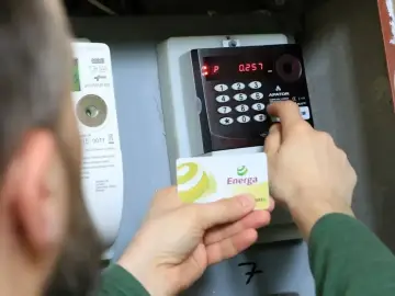 Osoba dokonuje doładowanie licznika przedpłatowego, wkładając kartę Energa i wpisując kod na klawiaturze.