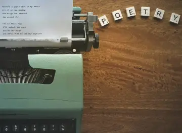 Maszyna do pisania z wierszem o papierowym ptaku i kostki z napisem POETRY. To nic dwa razy interpretacja wolności.