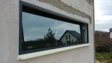 Montaż okna w bloku z betonu komórkowego. Pianka montażowa pod parapetem sugeruje, że ciepły parapet wady mogą być problemem.