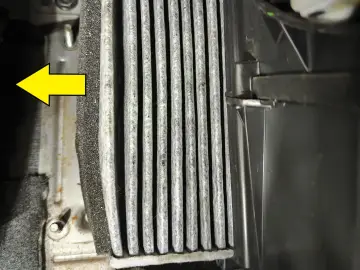 Zabrudzony filtr kabinowy Volvo XC60, wskazany strzałką, czeka na wymianę.