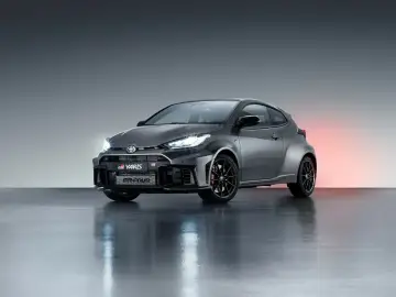 Szary Toyota GR Yaris GR-FOUR z agresywnym przednim zderzakiem i czarnymi felgami, gotowy do podboju dróg.