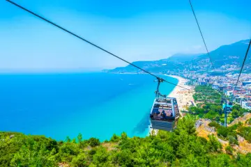 Kolejka linowa nad turkusowym morzem i plażą w Alanyi. Widok z góry na miasto i wybrzeże. Czy Alanya jest bezpieczna? Tak, wygląda na spokojną i piękną.