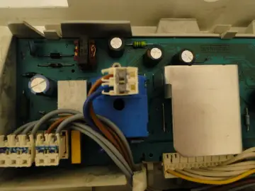 Płyta sterująca pralki Electrolux z błędem E40. Widoczne przekaźniki, kondensatory i złącza kablowe.