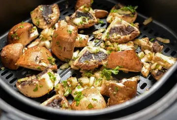 Pyszne pieczarki z airfryer, przyprawione i posypane natką pietruszki, gotowe do podania.