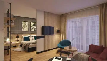 Przytulny pokój w hotelu Tulip Residences Warsaw Targowa. Łóżko, fotel, sofa i stolik kawowy tworzą komfortową przestrzeń.