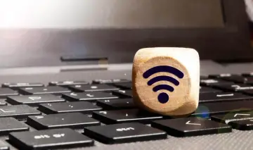 Drewniany sześcian z symbolem Wi-Fi na klawiaturze laptopa. Połączenie bezprzewodowe, czyli wifi direct, jest teraz na wyciągnięcie ręki.