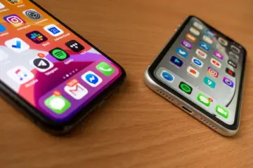 Dwa iPhone'y na drewnianym stole. Jeden z nich ma ikony aplikacji, jakby po udanym jailbreaku, z powiadomieniami.