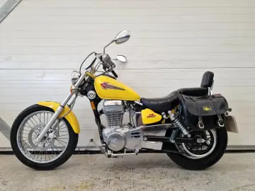 Żółty Suzuki Savage LS 650 z czarnymi sakwami i oparciem, gotowy na przygodę.