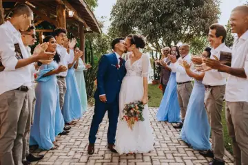 Un couple s'embrasse lors d'un mariage intime, entouré d'invités applaudissant.