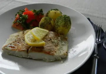 Filet z dorsza z piekarnika w folii, podany z ziemniakami i pomidorami.