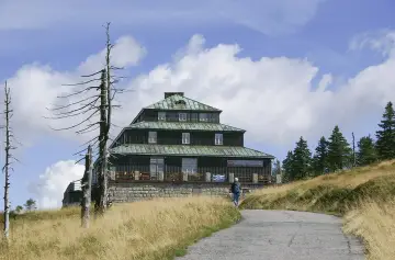 Schronisko Odrodzenie w Karkonoszach, z charakterystyczną architekturą i otoczone suchymi drzewami.