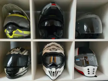 Sześć kasków motocyklowych w różnych kolorach i stylach, ułożonych w sześciu przegrodach.