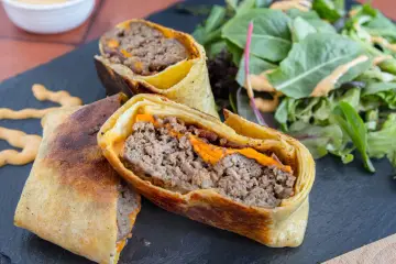 Herzhafte Burger Wraps mit geschmolzenem Käse und einem Beilagensalat.