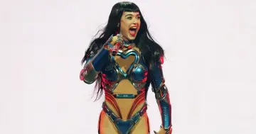 Katy Perry w futurystycznym stroju z sercami na scenie w Krakowie, z otwartymi ustami i błyszczącymi oczami.