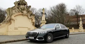 Elegancki Maybach S680 na tle zabytkowej architektury i drzew.
