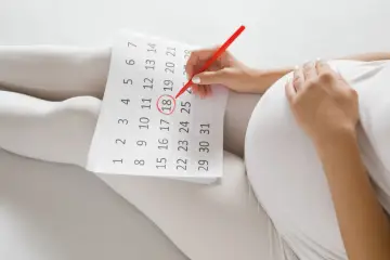 Ciężarna kobieta zaznacza na kalendarzu 18. dzień, licząc który tydzień ciąży.