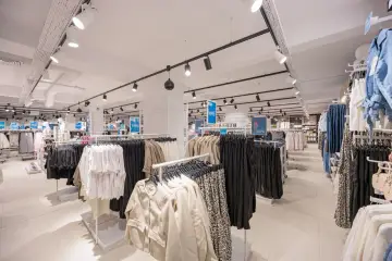 W sklepie LPP SA panuje porządek, ubrania wiszą na wieszakach, a ceny są widoczne.