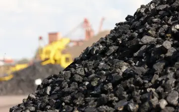 Góra węgla kamiennego, w tle maszyny górnicze. Zastanawiasz się, ile kosztuje tona węgla?