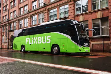 Zielony autokar FlixBus na mokrej ulicy. Wiele osób chwali sobie podróże tymi autobusami, a flixbus opinie są zazwyczaj pozytywne.