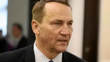 Minister spraw zagranicznych w garniturze i pasiastym krawacie, z uwagą wpatrujący się w dal.