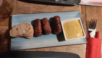 Mici e pane: un assaggio di cosa mangiare a Bucarest. Salsicce grigliate servite con pane fresco e senape.