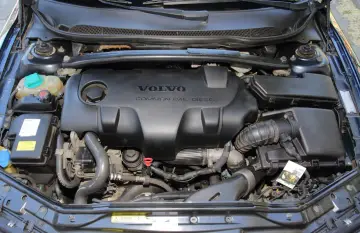 Silnik Volvo 2.4 D5 Common Rail Diesel. Widok komory silnika z widocznym czarnym plastikowym elementem osłaniającym.