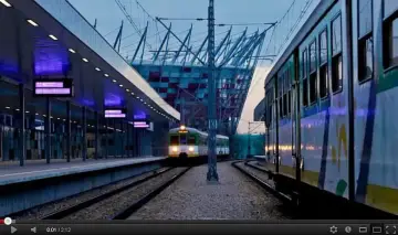 Pociągi na stacji Warszawa Stadion PKP, z nowoczesnym stadionem w tle.