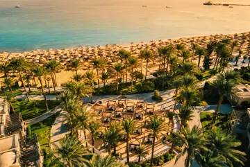 Rajska plaża w Egipcie z rzędami leżaków i palm. Widok z lotu ptaka na luksusowy kurort, idealny na wakacje.