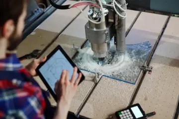 Operator kontroluje pracę frezarki CNC na tablecie, która precyzyjnie wycina wzór. To pokazuje, cnc co to za technologia.