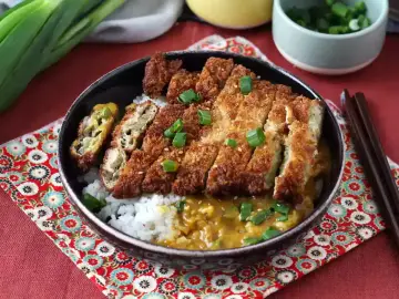 Chrupiące katsu na ryżu z sosem curry, posypane szczypiorkiem. Pyszne danie, które z pewnością zaspokoi głód.