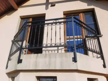 Solidne mocowania balustrady balkonowej z kutego żelaza, ozdobione misternymi wzorami, zapewniają bezpieczeństwo i elegancję.