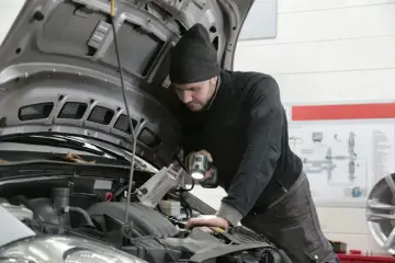 Mechanik z latarką bada silnik Renault, szukając przyczyny błędu DTC P0300.