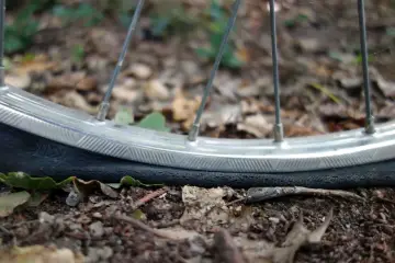 Płaskie koło rowerowe na ziemi. Czas dowiedzieć się, jak napompować koło w rowerze, by wrócić na trasę.