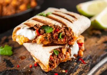 Pyszne burrito przepis: soczyste mięso mielone, ciecierzyca, papryczka chili i śmietana, podane na desce.
