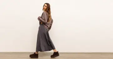 Modelka w luźnej, szarej spódnicy i brązowej bluzce. Idealny zestaw, który pokazuje, co pasuje do szarej bluzki.