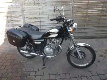 Czarny motocykl Suzuki GN125 z kuframi, gotowy na podróż.