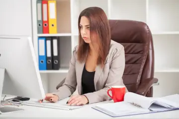 Kobieta w biurze pracuje przy komputerze, zastanawiając się, czy staż z urzędu pracy wlicza się do stażu pracy.