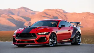 Czerwony mustang shelby z czarnymi pasami i spojlerem na tle pustynnych gór.