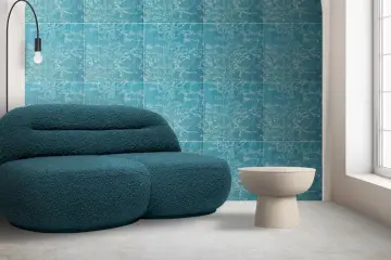 Divano blu petrolio davanti a una parete con motivo floreale su sfondo colore verde acqua. Tavolino beige e lampada nera.