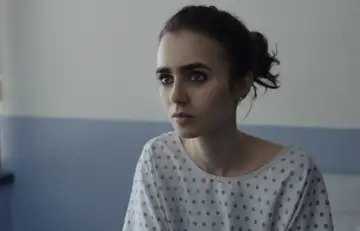 Lily Collins w szpitalnej koszuli, w kadrze z jednego z jej poruszających filmów.