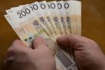 Dłonie trzymają plik banknotów 200 zł. Czy to już więcej niż najniższa krajowa netto?