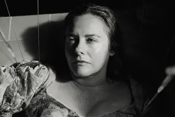 Alicia Silverstone w mrocznym kadrze, jakby marionetka w jednym z jej filmów.